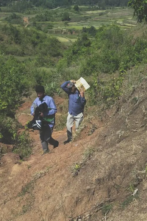 2 men carrying supplies up a hillside