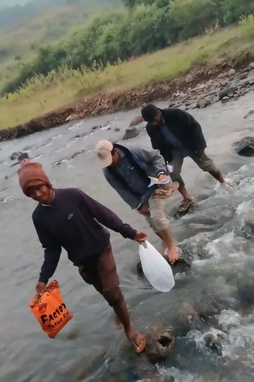 3 men crossing a river on foot