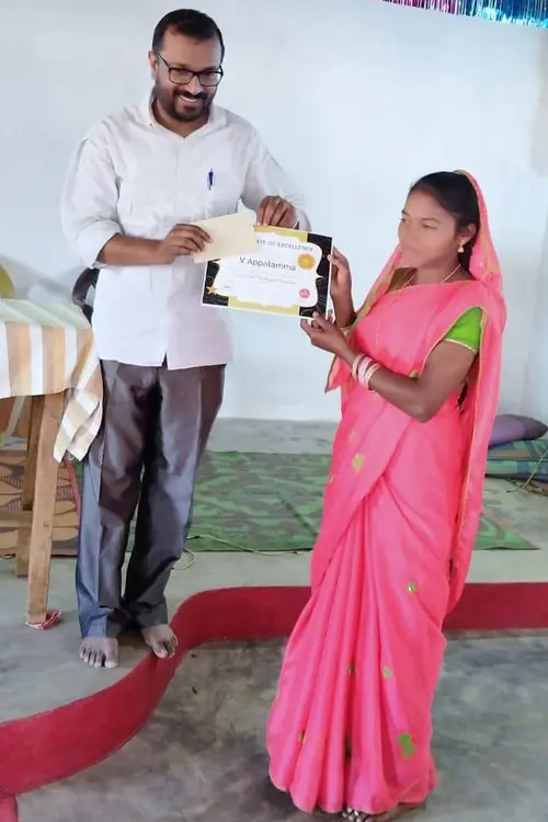 man handing a certificate to a young woman in a public ceremony